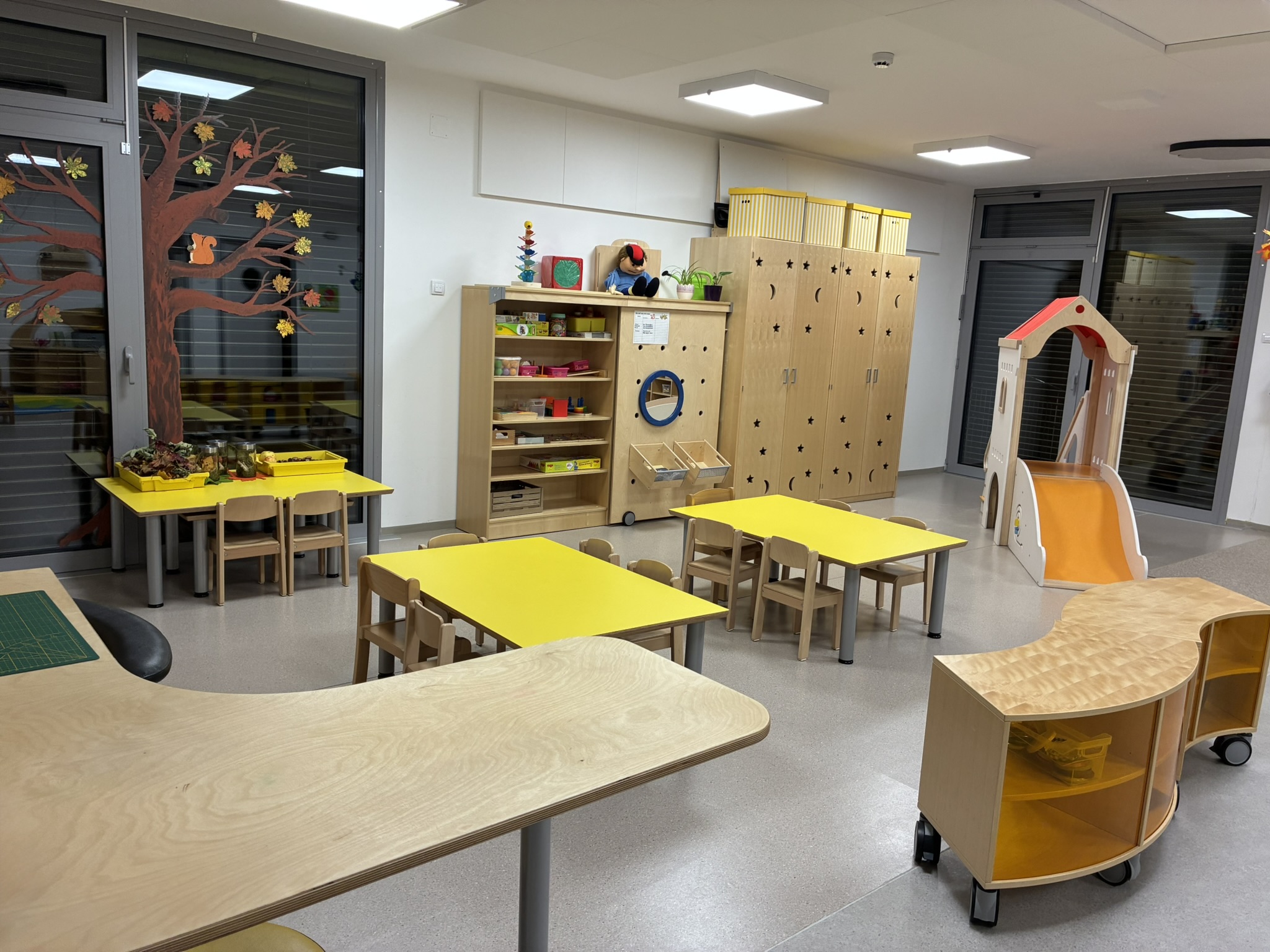 ein Spielraum mit vielen Tischen, Stühlen und Arbeitsbereichen